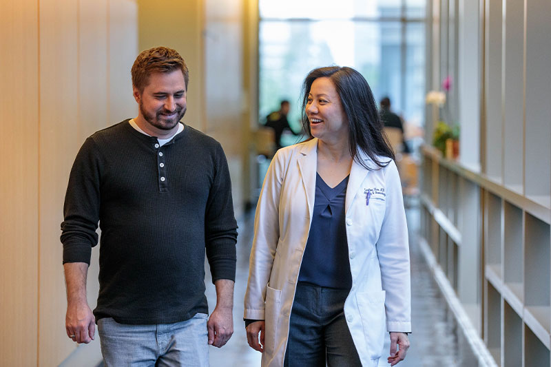 Doctor and patient converse while walking down a hallway